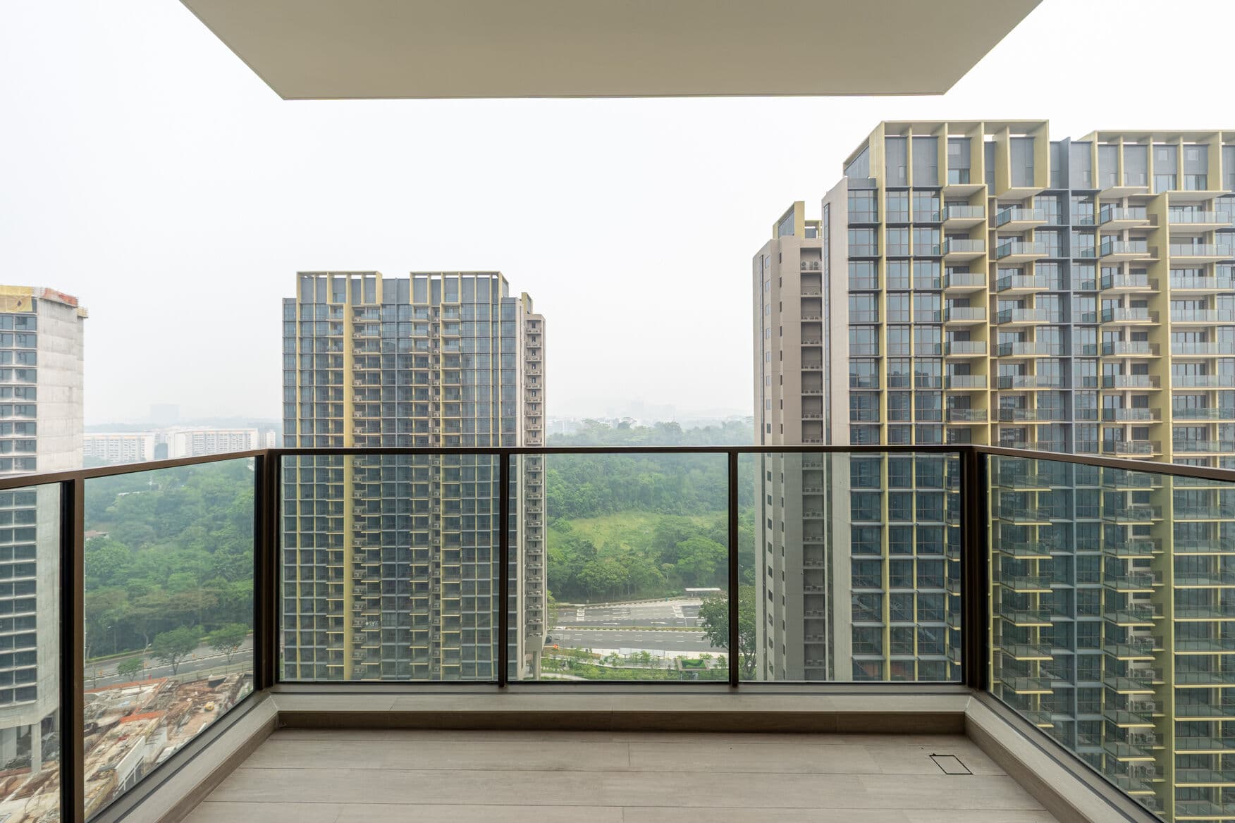 Balcony with a glass railing looking out over greenery between neighbouring residential towers